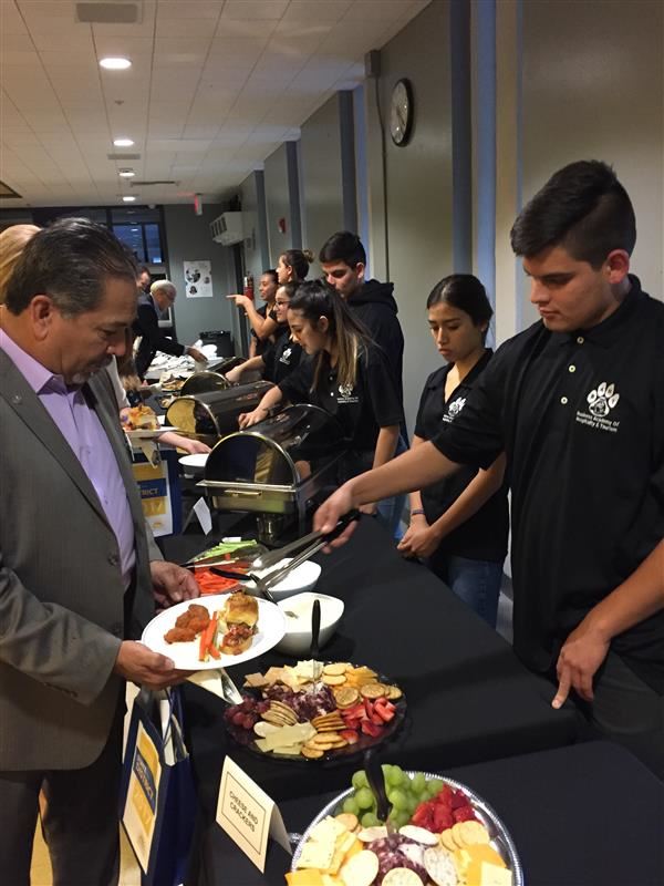 Photo of high school culinary students serving food buffet style to adult guests